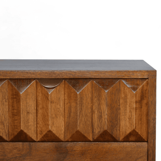 Close-up of the carved prism pattern on the mango wood nightstand’s top drawer, emphasizing fine craftsmanship and natural chestnut tones