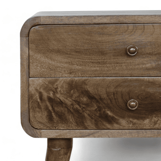 Close-up of the grey-washed mid-century modern nightstand showing its smooth curved edges and two drawers with round brass knobs.