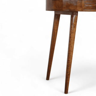 Close-up of the tapered legs of the round wooden table with a natural chestnut finish.