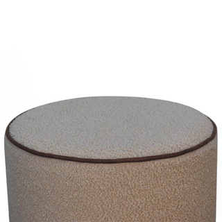 Angled view of the Cream Bouclé Ottoman showcasing its plush upholstered surface and rounded edges with contrast stitching.
