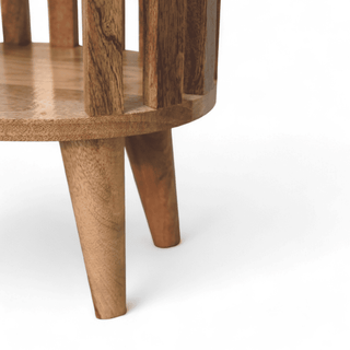 Close-up of tapered legs on round mango wood nightstand, emphasizing sturdy design and mid-century modern style